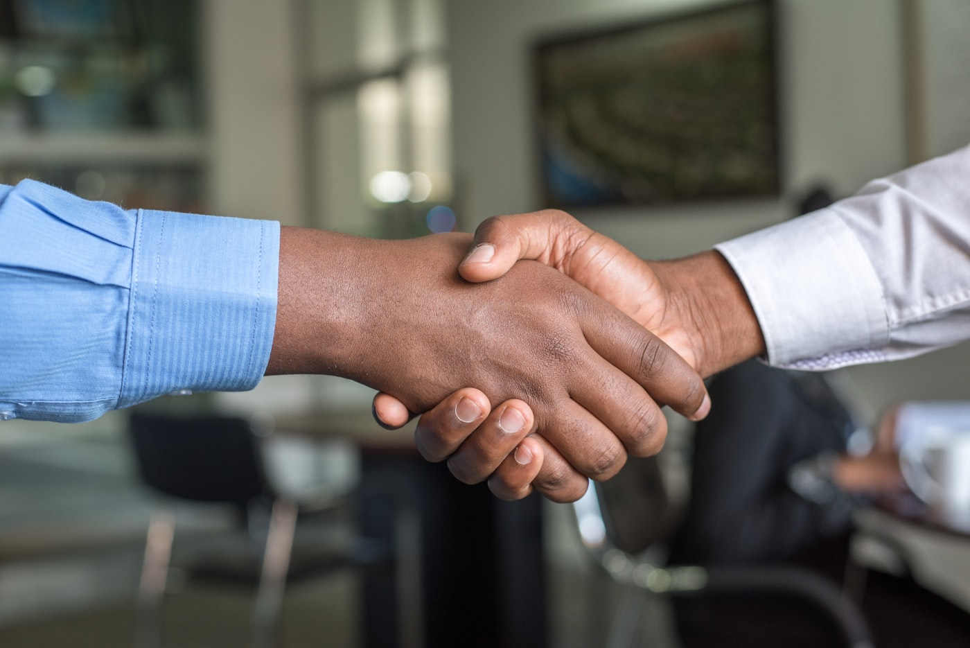Two professionals shaking hands across a desk after agreeing loan terms